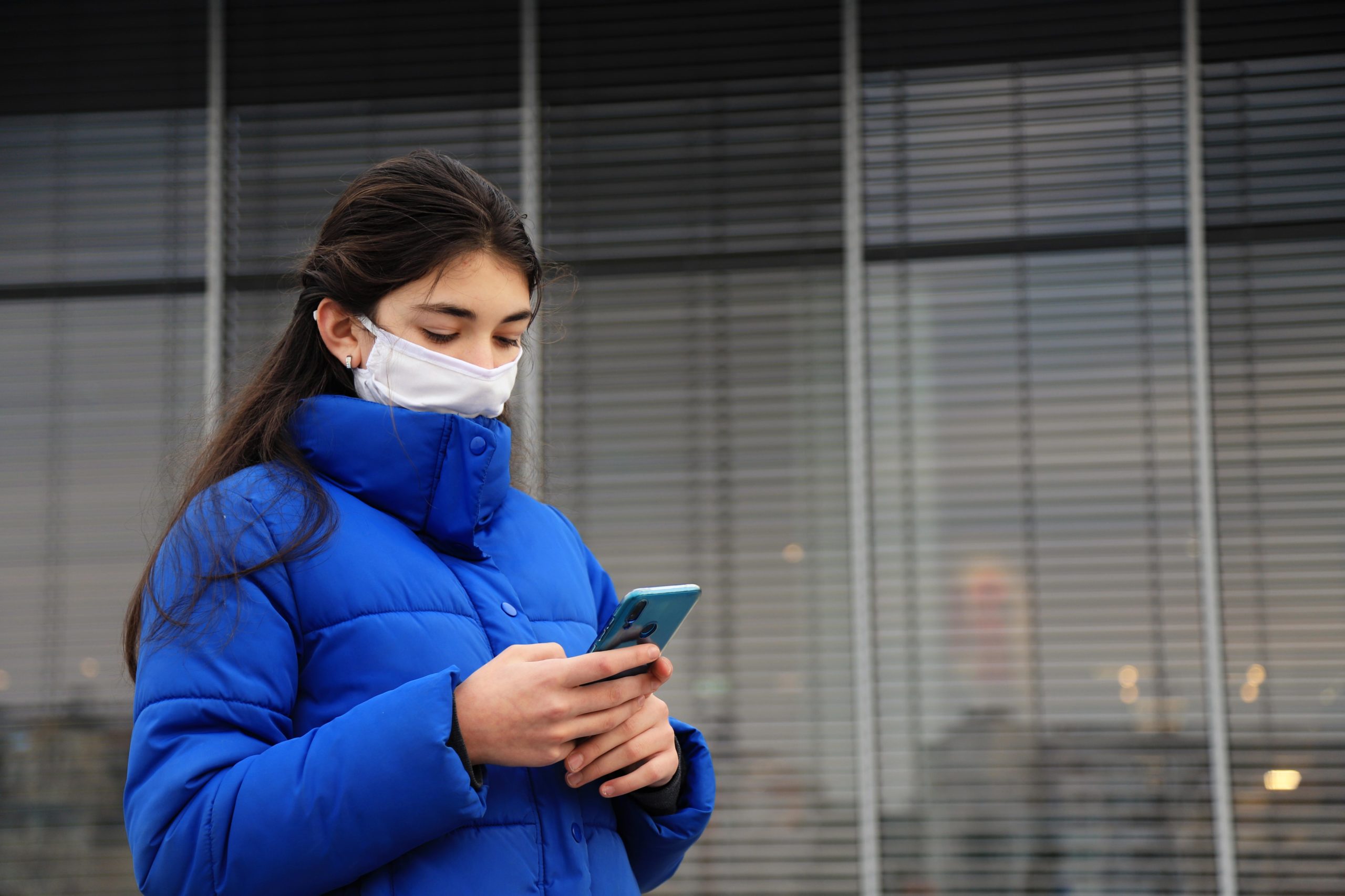 Young woman using a cell phone wearing a mask