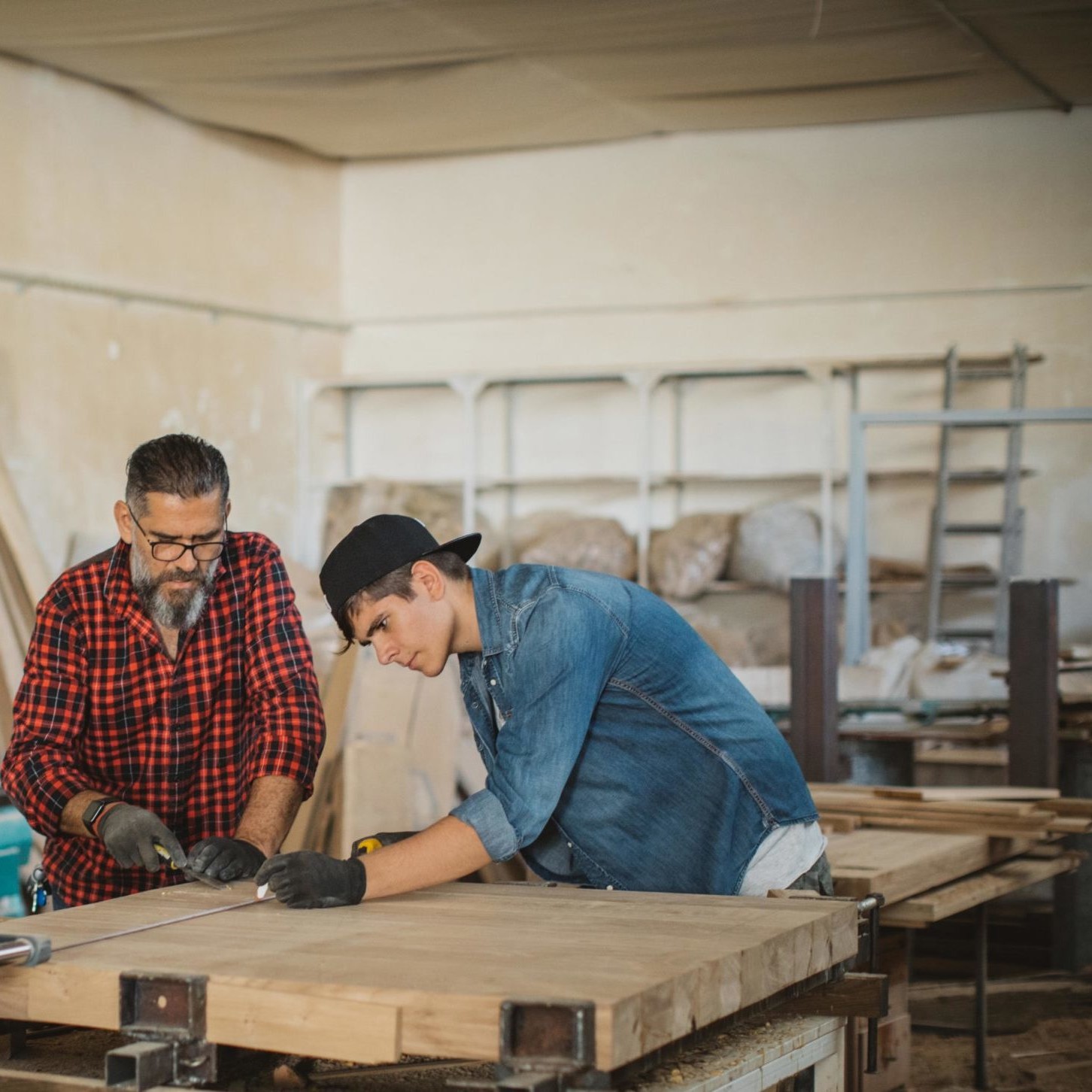Father and teenage son work in woodshop together