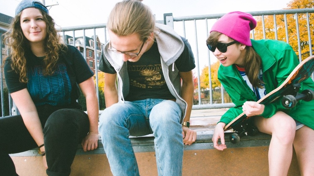 Three friends hanging out at the skate park