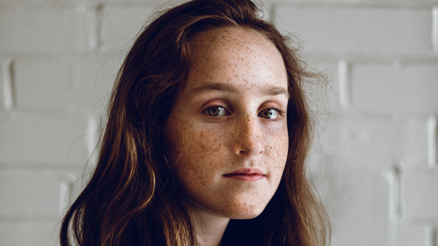 Young freckled girl half smiles while facing the camera